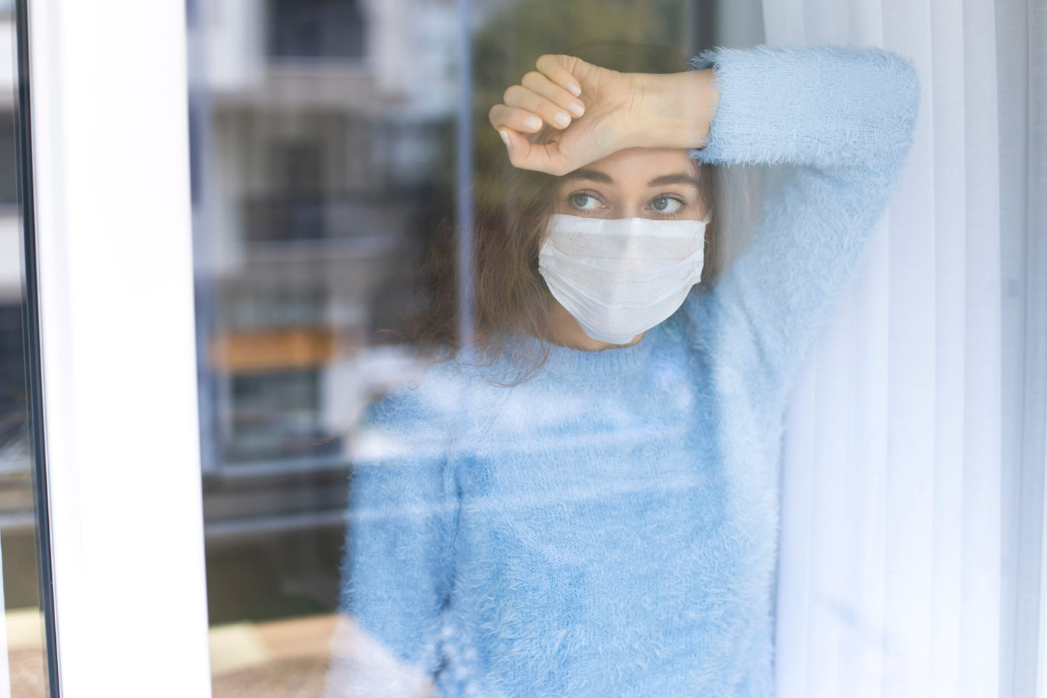 A tired health care worker looks out the window.