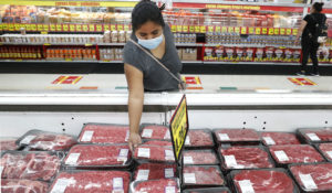 In this April 29, 2020 file photo, a shopper wears a mask as she looks over meat products at a grocery store in Dallas.(AP Photo/LM Otero, File)