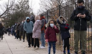 Children wait with their father in a line spanning several blocks in order to be tested for COVID-19, Tuesday, Dec. 21, 2021, at a Curative testing kiosk outside an elementary school in northwest Washington. (AP Photo/Jacquelyn Martin)