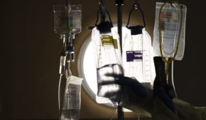 A nurse checks on IV fluids while talking to a COVID-19 patient at Providence Holy Cross Medical Center in Los Angeles in 2021. (AP Photo/Jae C. Hong, File)