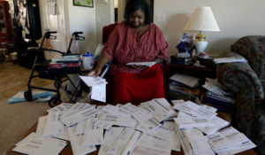 Debra Smith, 57, sorts through her medical bills in her living room on Thursday, Oct. 7, 2021, in Spring Hill, Tenn. Smith, who has health problems that prevent her from working, has about $10,000 in unpaid medical bills. (AP Photo/Mark Zaleski)