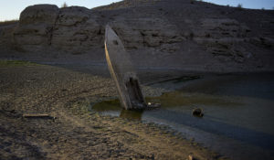 A formerly sunken boat sits upright into the air with its stern stuck in the mud along the shoreline of Lake Mead at the Lake Mead National Recreation Area, Friday, June 10, 2022, near Boulder City, Nev. Lake Mead water has dropped to levels it hasn't been since the lake initially filled over 80 years ago. (AP Photo/John Locher)