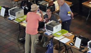 A voter talks with poll workers before casting his ballot, Monday, Aug. 8, 2022, at the Stephen P. Clark Government Center in Miami. (AP Photo/Wilfredo Lee)