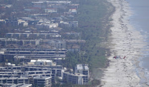 A Coast Guard helicopter flies over damaged homes and buildings in the aftermath of Hurricane Ian, Thursday, Sept. 29, 2022, on Sanibel Island, Fla. (AP Photo/Wilfredo Lee)