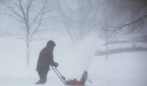 A person clears snow as a winter storm rolls through western New York on Dec. 24 in Amherst N.Y. The storm knocked out power to hundreds of thousands of homes and businesses over the weekend as it swept across the United States. (AP Photo/Jeffrey T. Barnes)