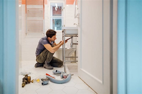 Man fixing bathroom sink plumbing.