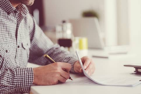 Man signing documents at desk.