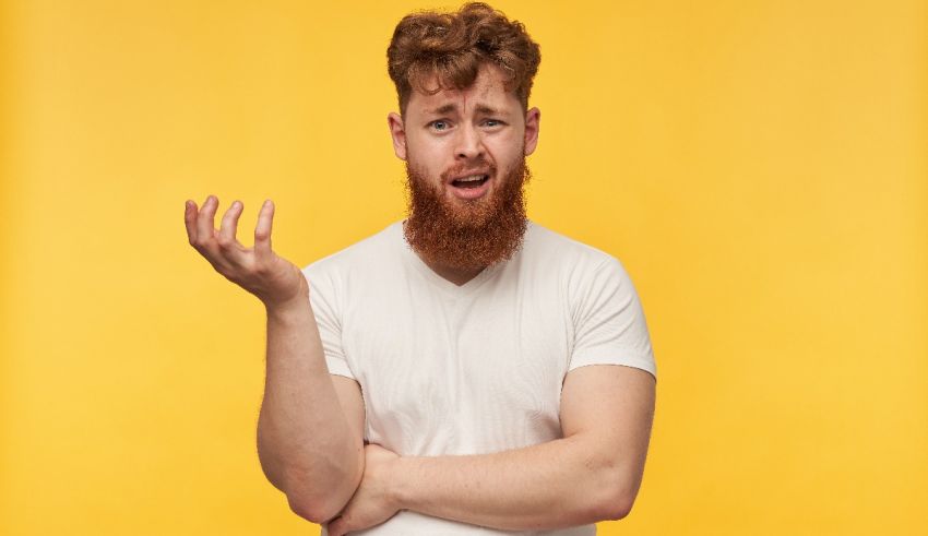 A man with a beard is holding his hands up in front of a yellow background.