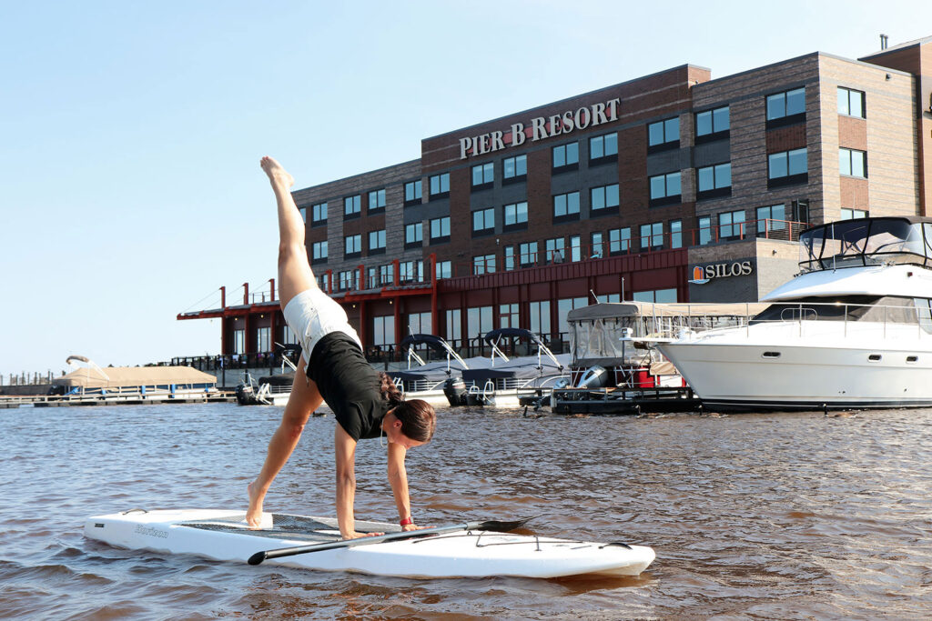 Pier B Resort, Rawfish Media, Baxter, MN, Minnesota marketing specialists, social media management services, photography, videography, brand development, storytelling, woman doing yoga on a white paddleboard