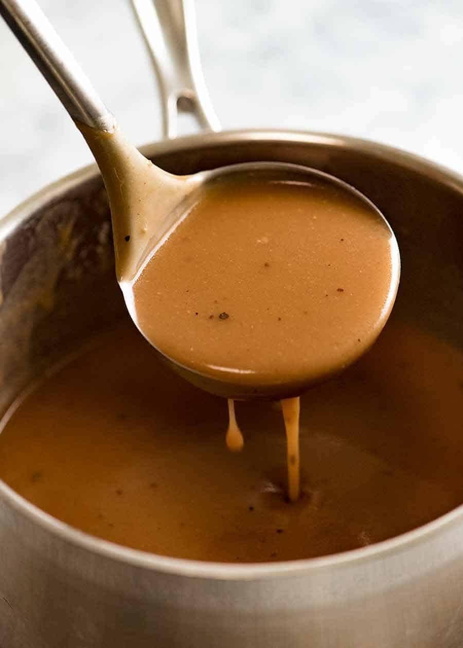 Ladle scooping up gravy from saucepan