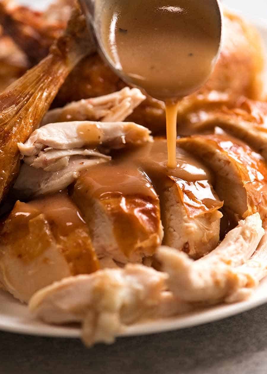 Gravy being poured over roast chicken