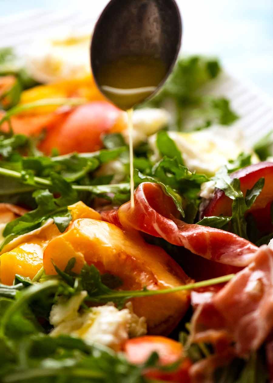 Drizzling lemon dressing over peach salad