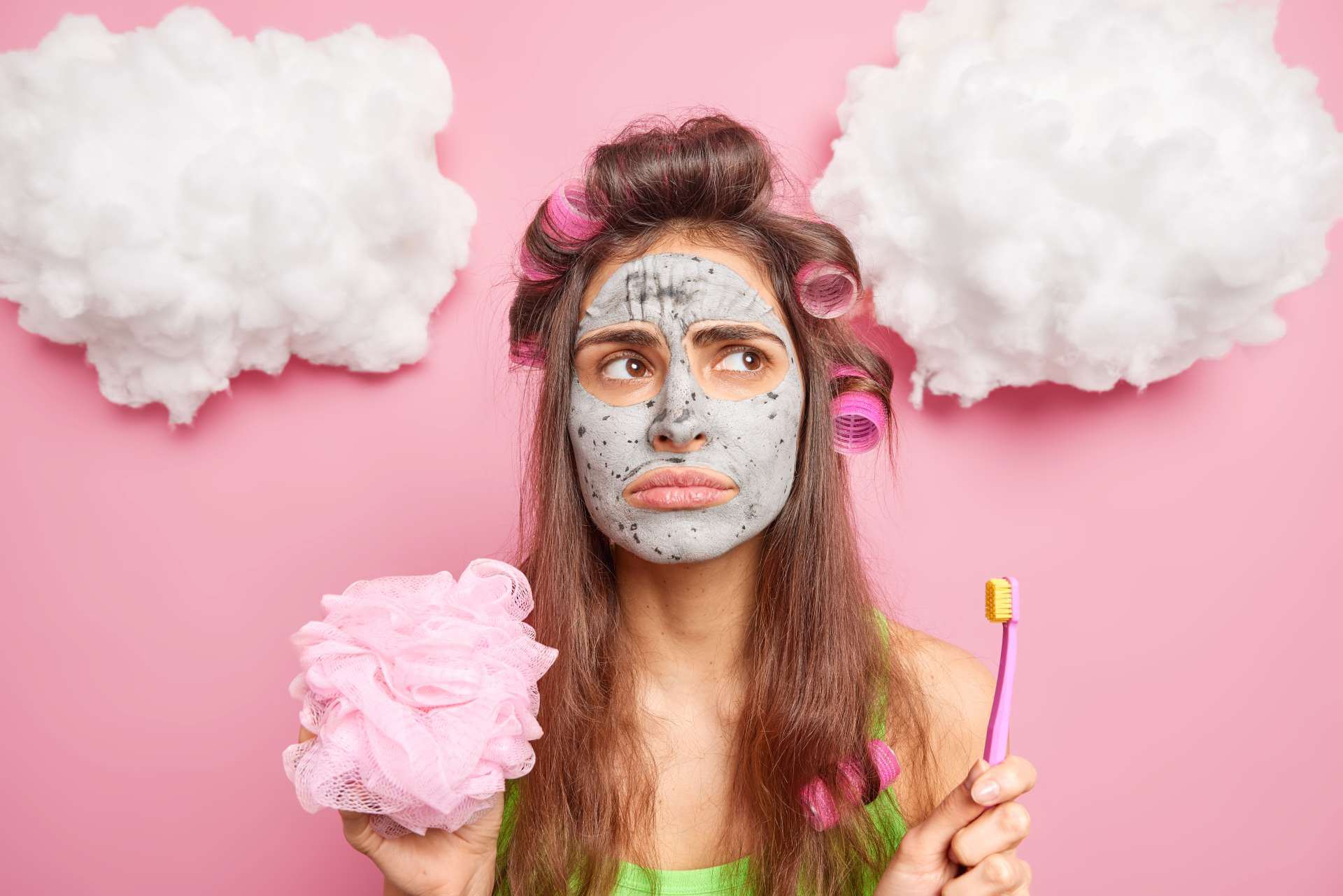 Female with mask applied making beauty and skin care decision making on pink background