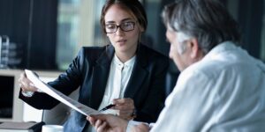 A man and a woman in business attire review a financial document.