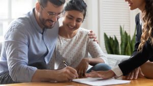 A man and woman hold each smiling other while signing a document.