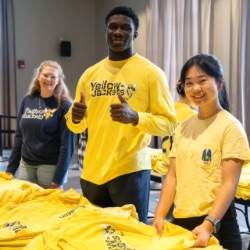 Three University of Rochester sophomores posed together while wearing University of Rochester hats. 