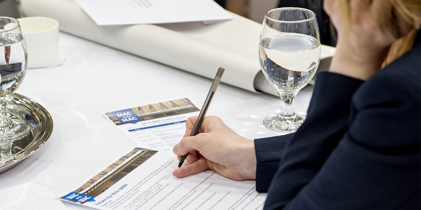 A person writing notes at a conference table.