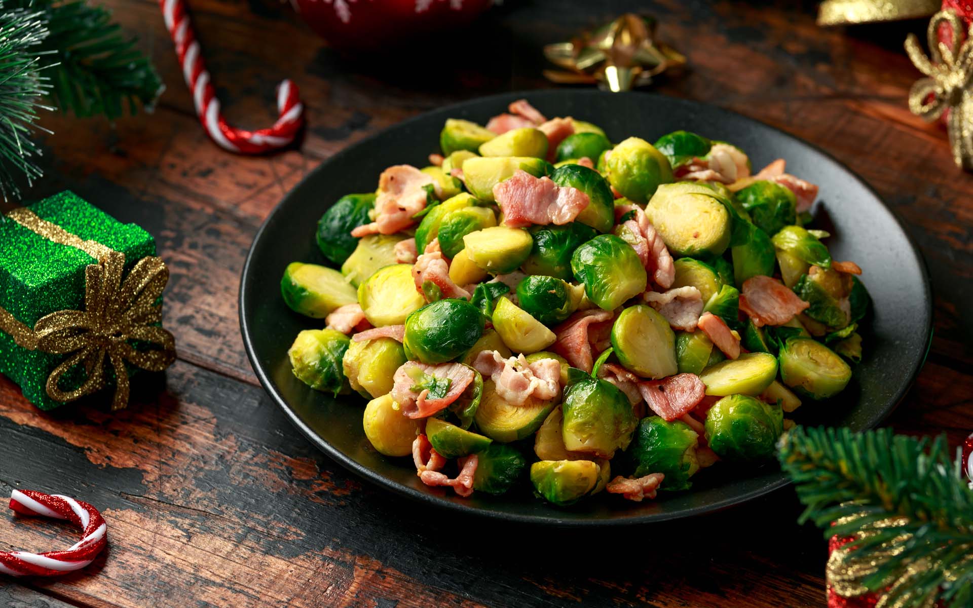 A plate of Brussels sprouts cooked with bacon displayed on a table with Christmas decoration