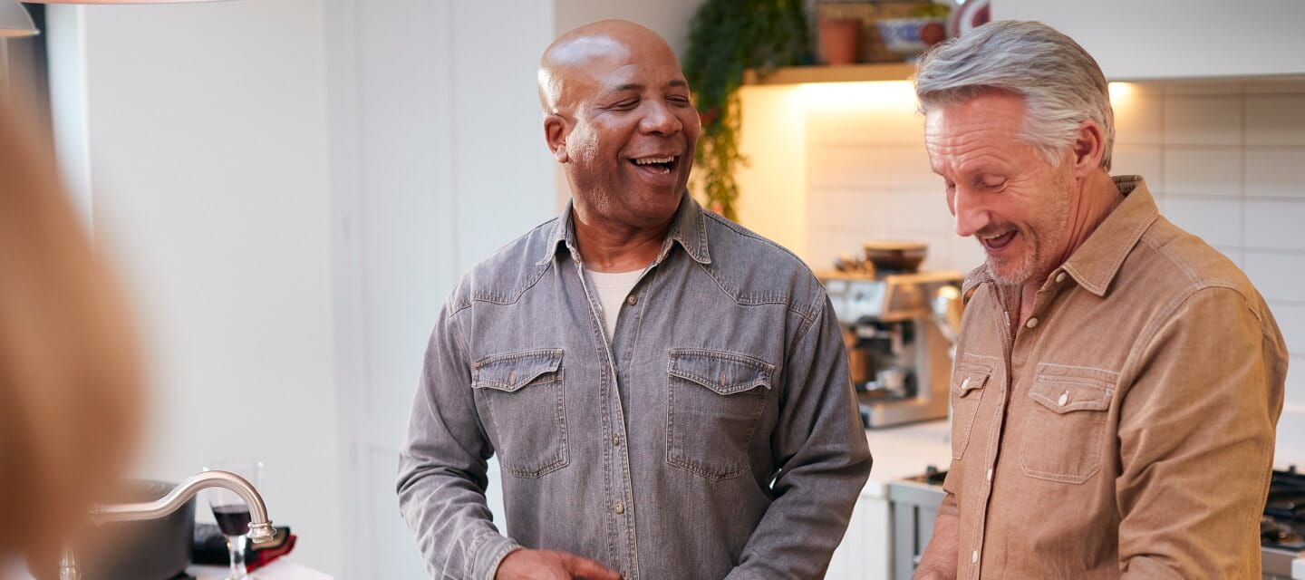 Two middle-aged men sharing a joke in the kitchen