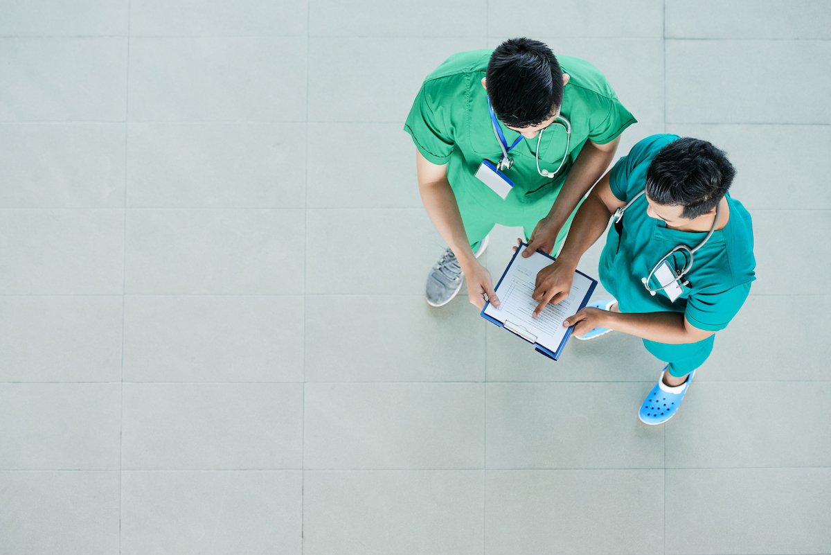 Two doctors standing on a tiled hospital floor. 