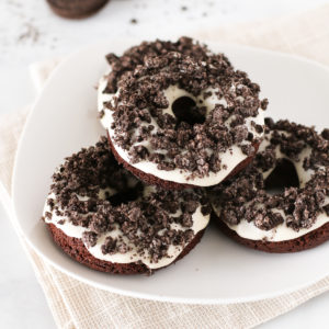 Gluten Free Vegan Cookies N’ Cream Donuts. Baked chocolate donuts with a vanilla glaze, covered with crushed Oreo cookies. Oh so tasty!