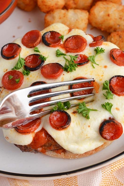 fork cutting into an open face pizza burger