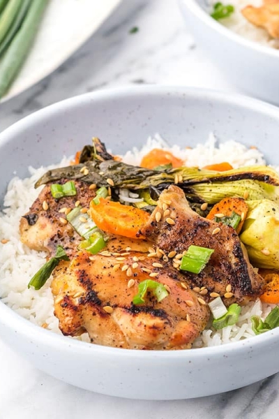 close up angled shot of honey garlic chicken in a bowl with rice