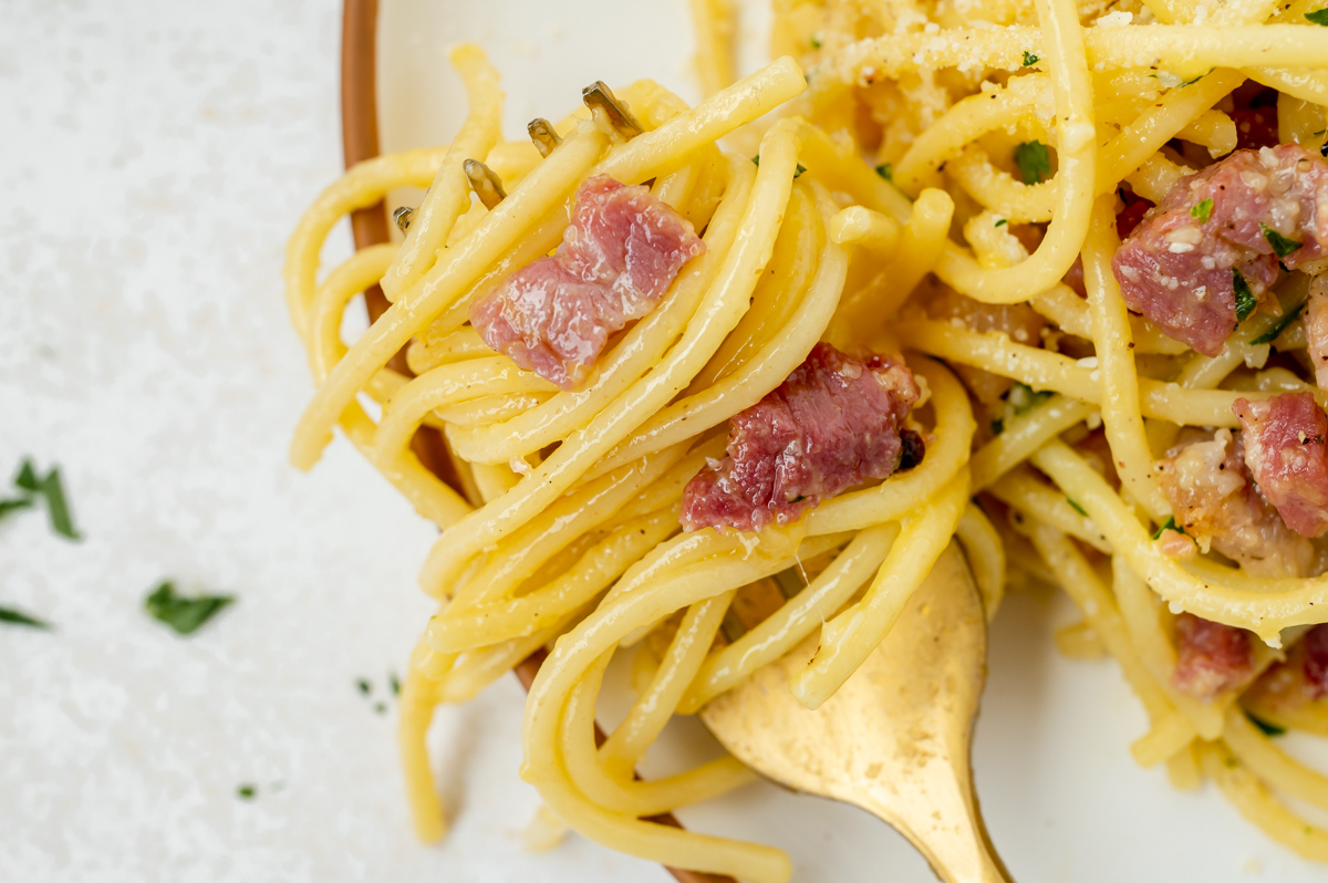 close up overhead shot of twirl of pasta and pancetta on fork