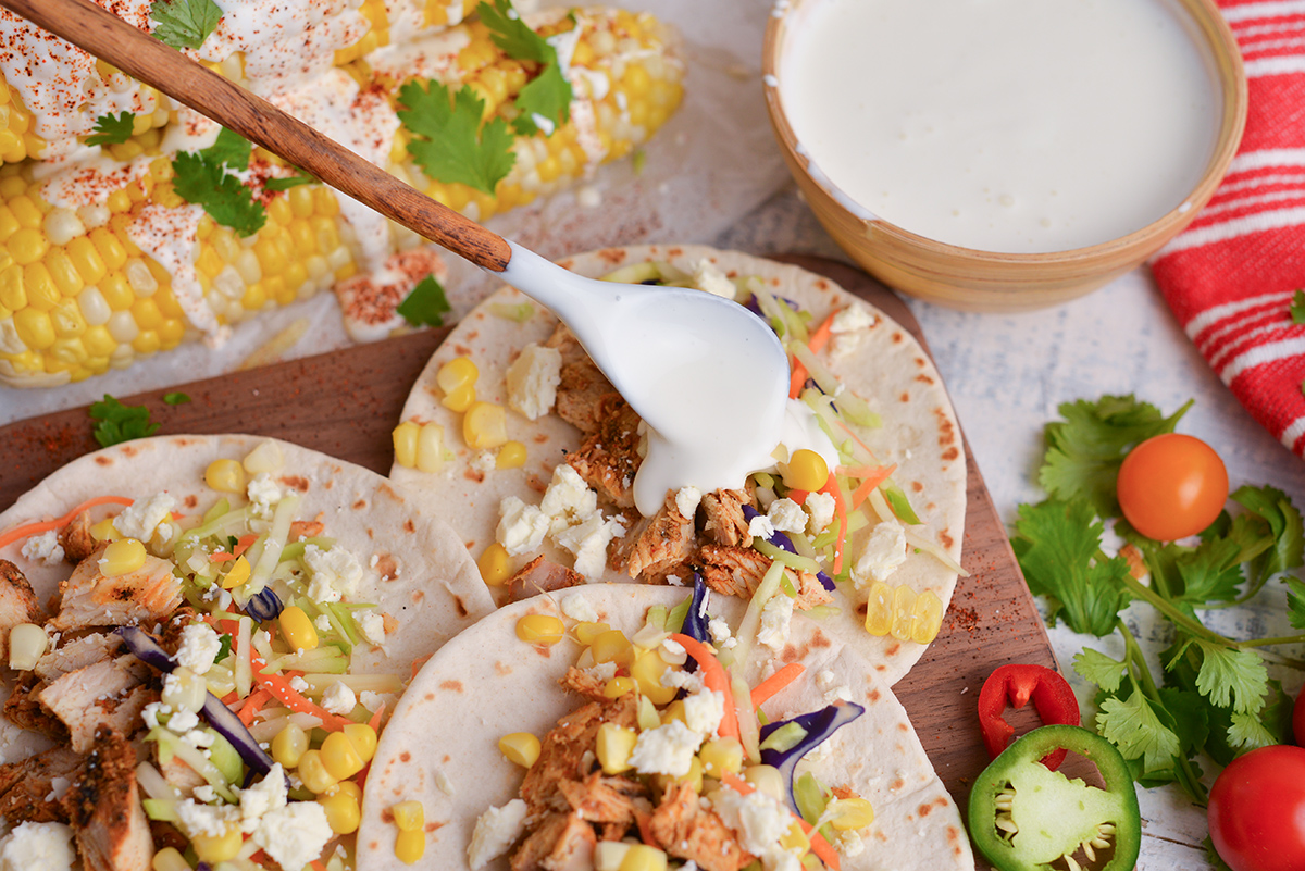 overhead shot of spoon adding crema mexicana to tacos