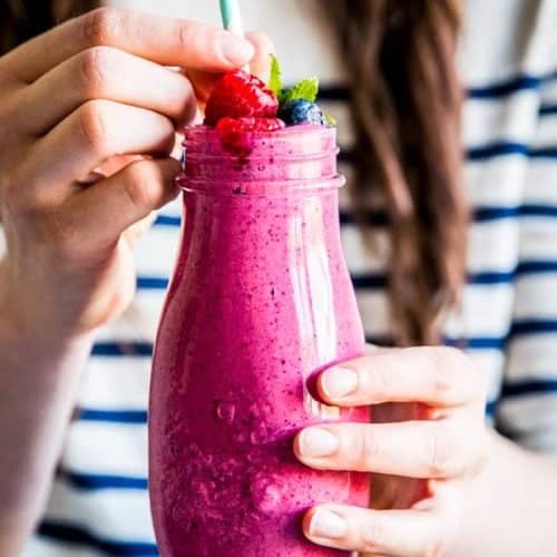 woman holding a bottle of berry smoothie