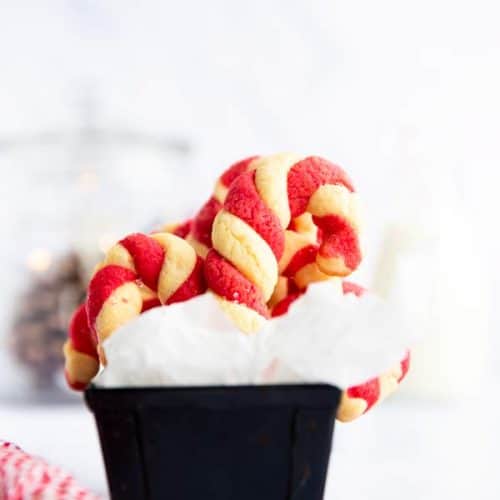 black loaf pan lined with parchment paper and filled with candy cane cookies