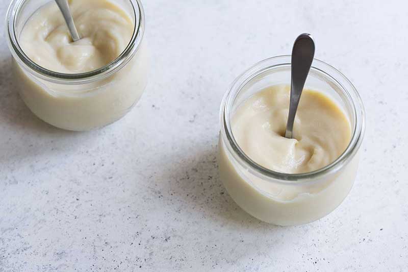 Homemade vanilla pudding in mason jars with spoons.