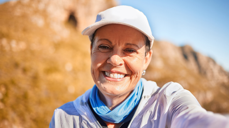 Woman taking smiling selfie in nature