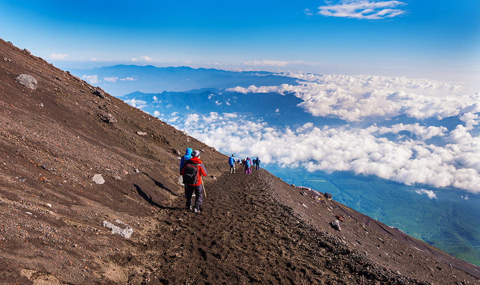 A row of people walking along the top of Mount Fuji