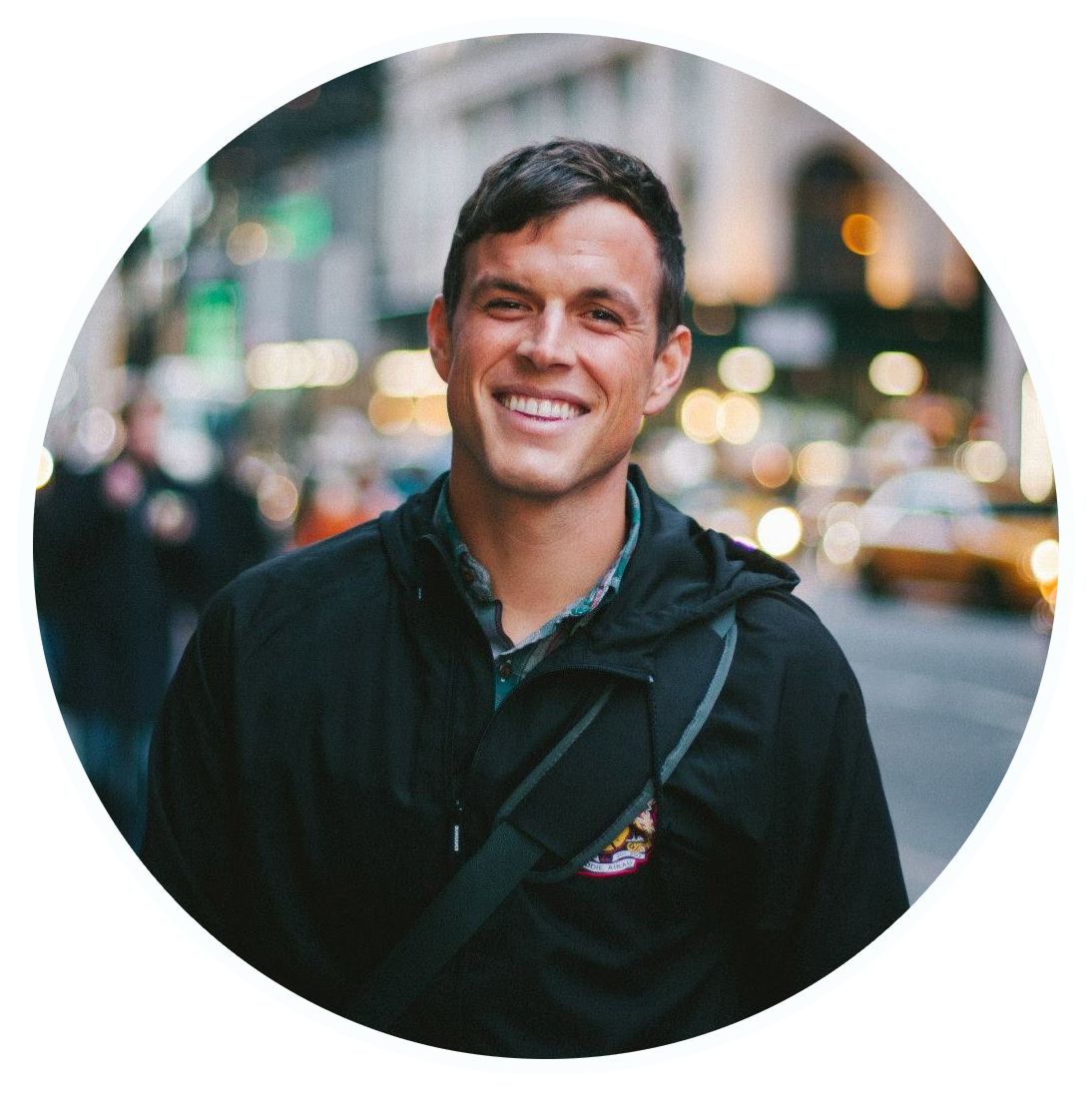 Caucasian man with light brown hair standing on a city street smiling