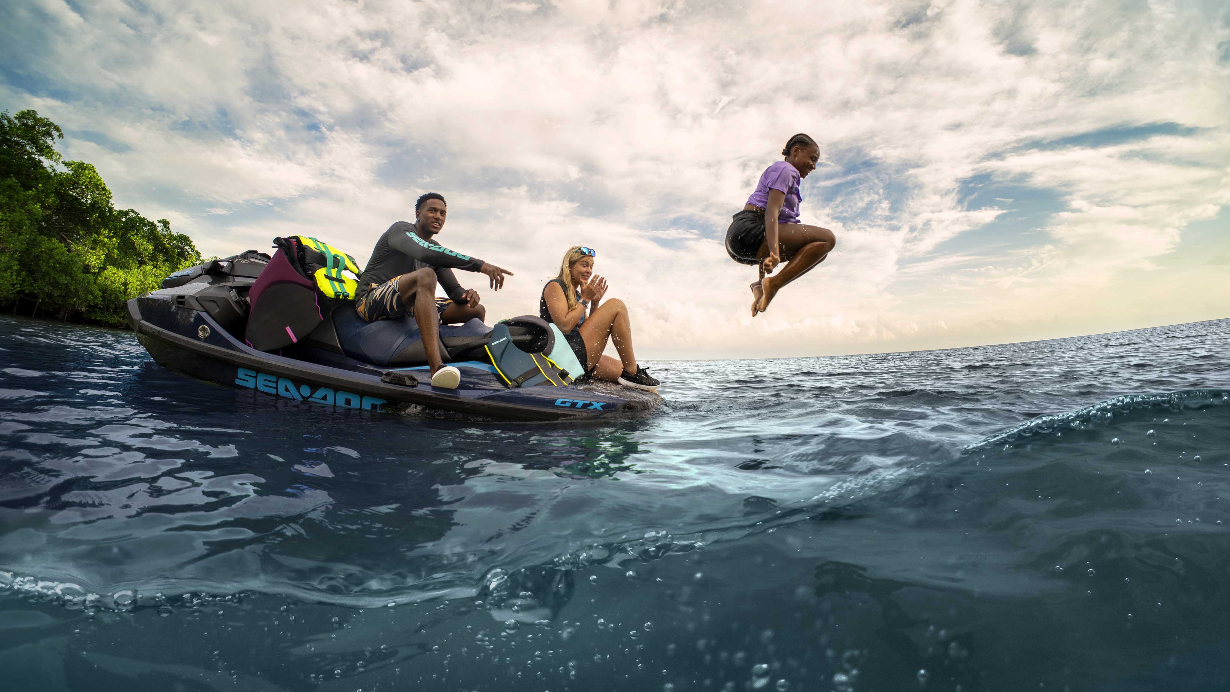 Three people swiming next to a Sea-Doo GTX