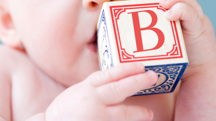 Close up of baby biting on alphabet block