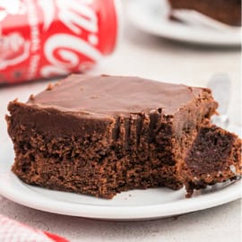 Slice of chocolate coca cola cake with a bite taken out.