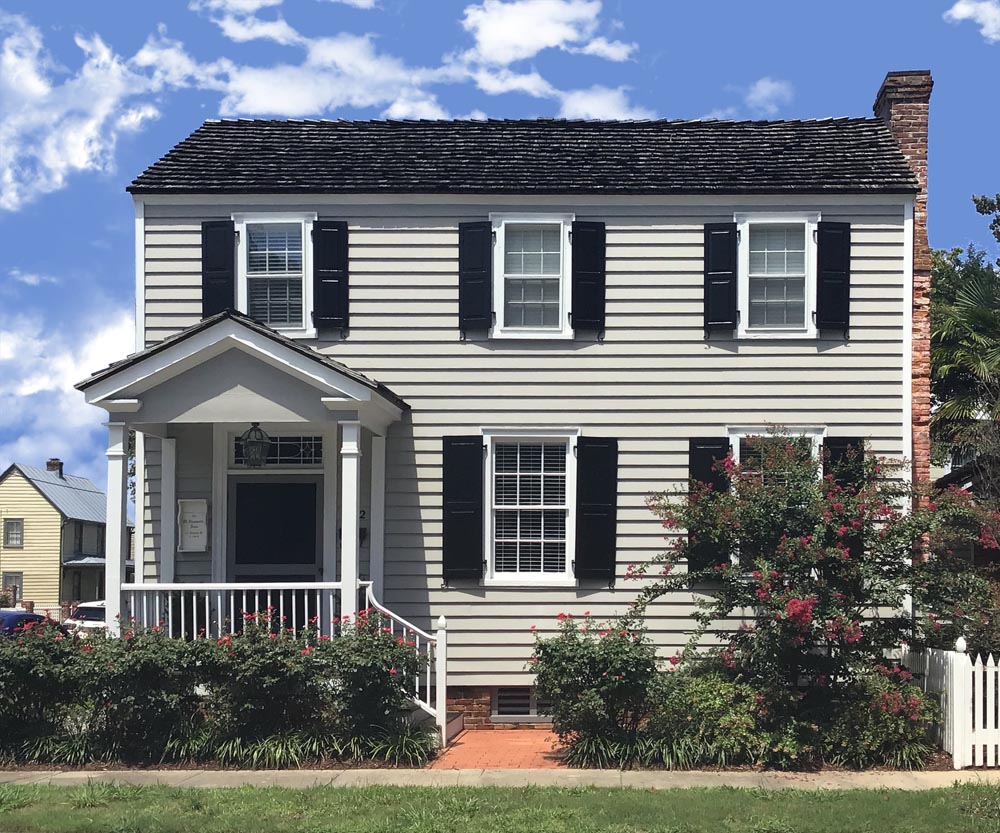 Black raised panel custom exterior shutters installed on a two-story house. 