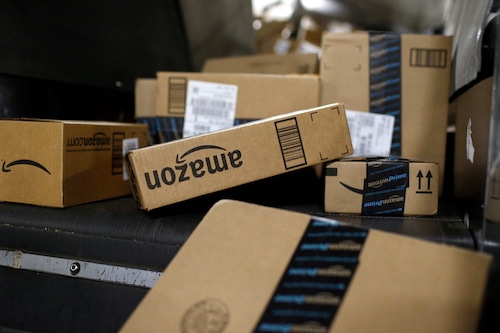 An assortment of Amazon-branded packages in a jumble on a conveyor belt