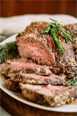 Garlic Butter Beef Roast on a serving plate with some if the roast sliced.