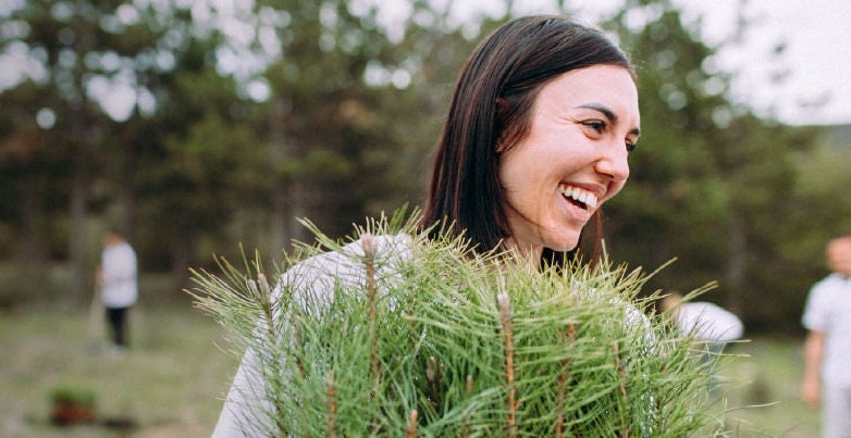 Woman holding  green branches from tree.