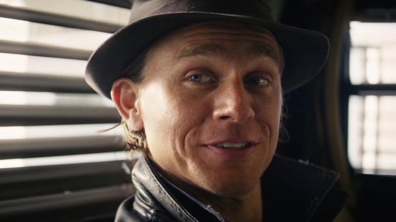 Charlie Hunnam as Charlie Waldo grinning with a hat on in Last Looks