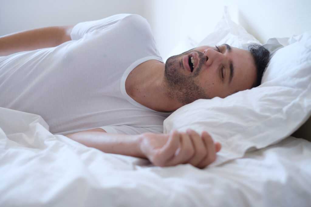 Man snoring and lying in the bed.