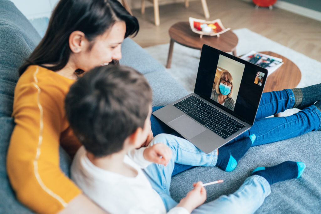 Young woman and her son in quarantine at home having video call with grandmother