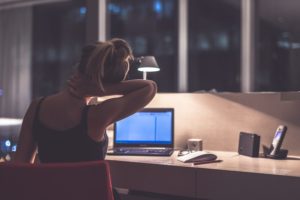 A woman stretching her neck while working from home.