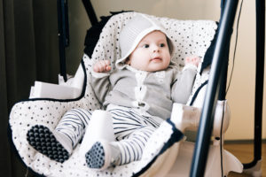 Cute baby sitting in a high chair, swings