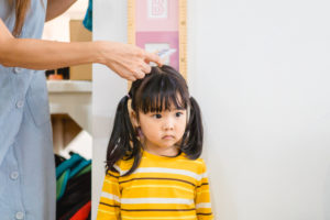 Mother measuring the height of her daughter