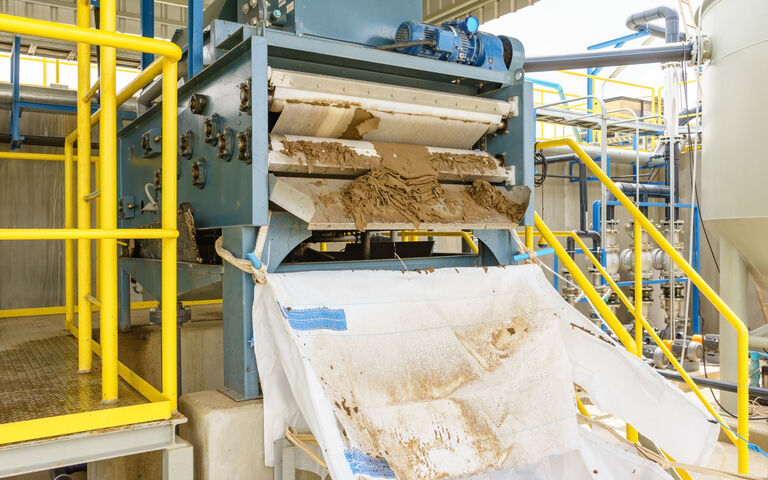 Cake being discharged from a sludge dewatering belt filter press