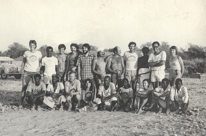 A black and white field photograph of 20 people, standing in 2 rows of 10